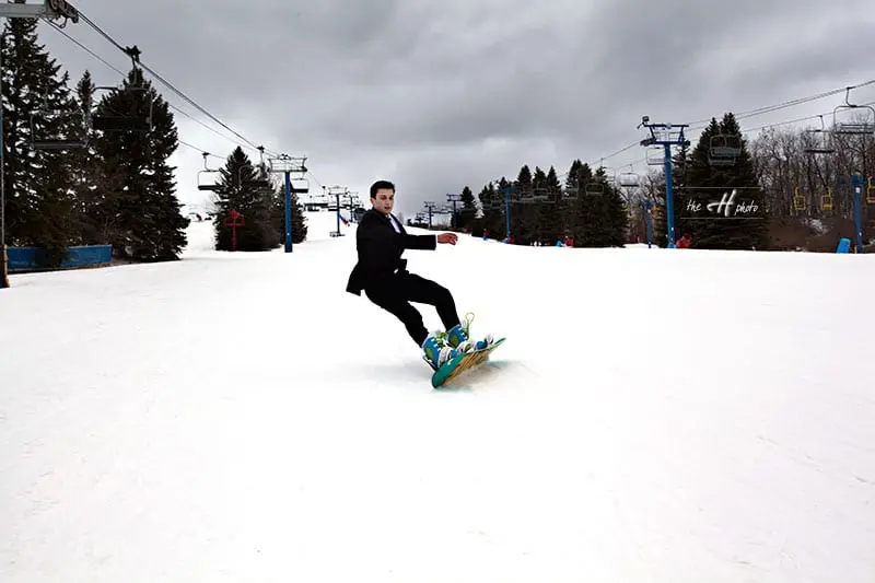 Groom sliding on snowboard photos of trash the dress in snow