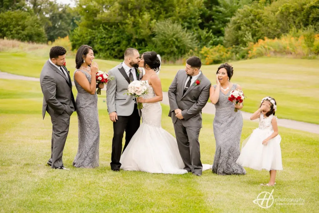 Bridal party making fanny faces while the bride and groom kiss. bridal-party