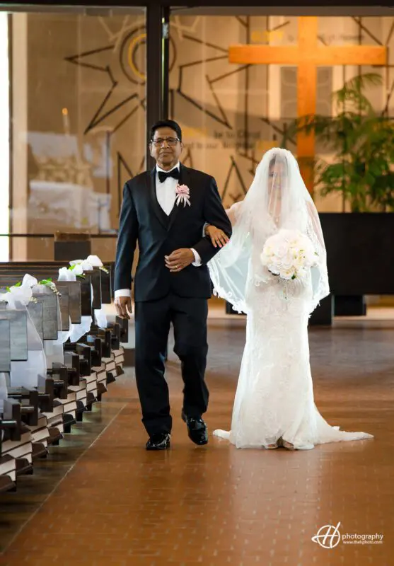 Bride walking down the aisle with her father. Vonetta walking down the aisle at St. John Brebeuf's Church next to her father