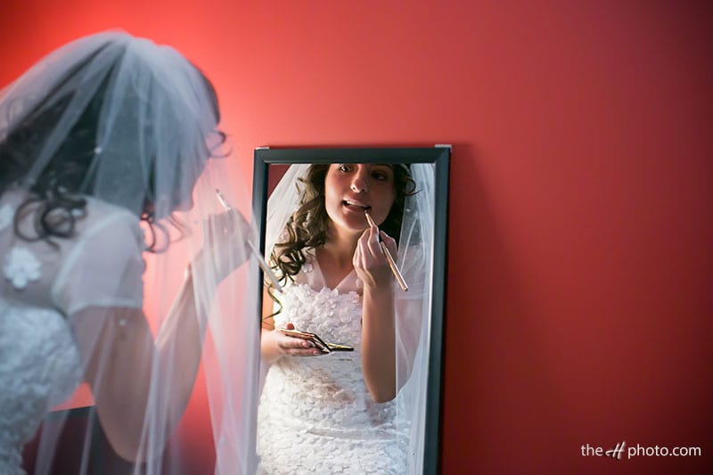 bride getting dressed and tocuh up in the mirror