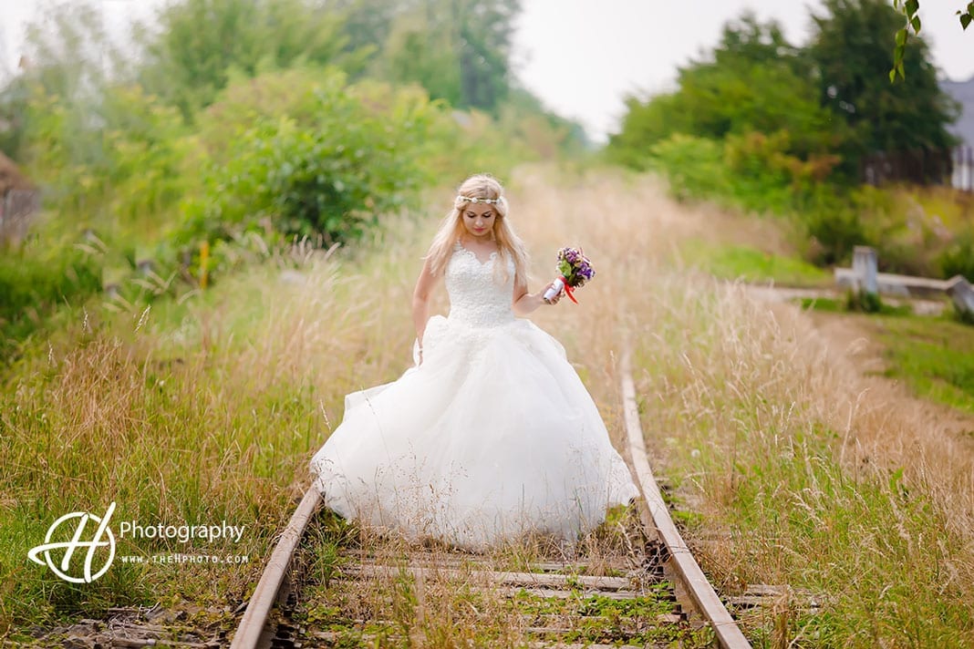 Bride walking on old train rails.