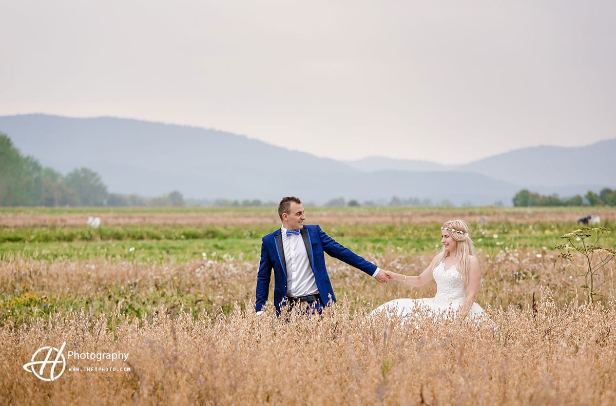 Couple posing over a field with grains.
