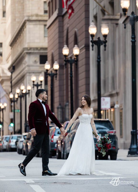 Samuel and Faith take a stroll in front of the iconic Chicago Board of Trade building, surrounded by bustling city streets. They walk hand in hand, with Samuel carrying a backpack and Faith holding a coffee cup. The towering building behind them is a symbol of Chicago's financial history and architectural beauty.