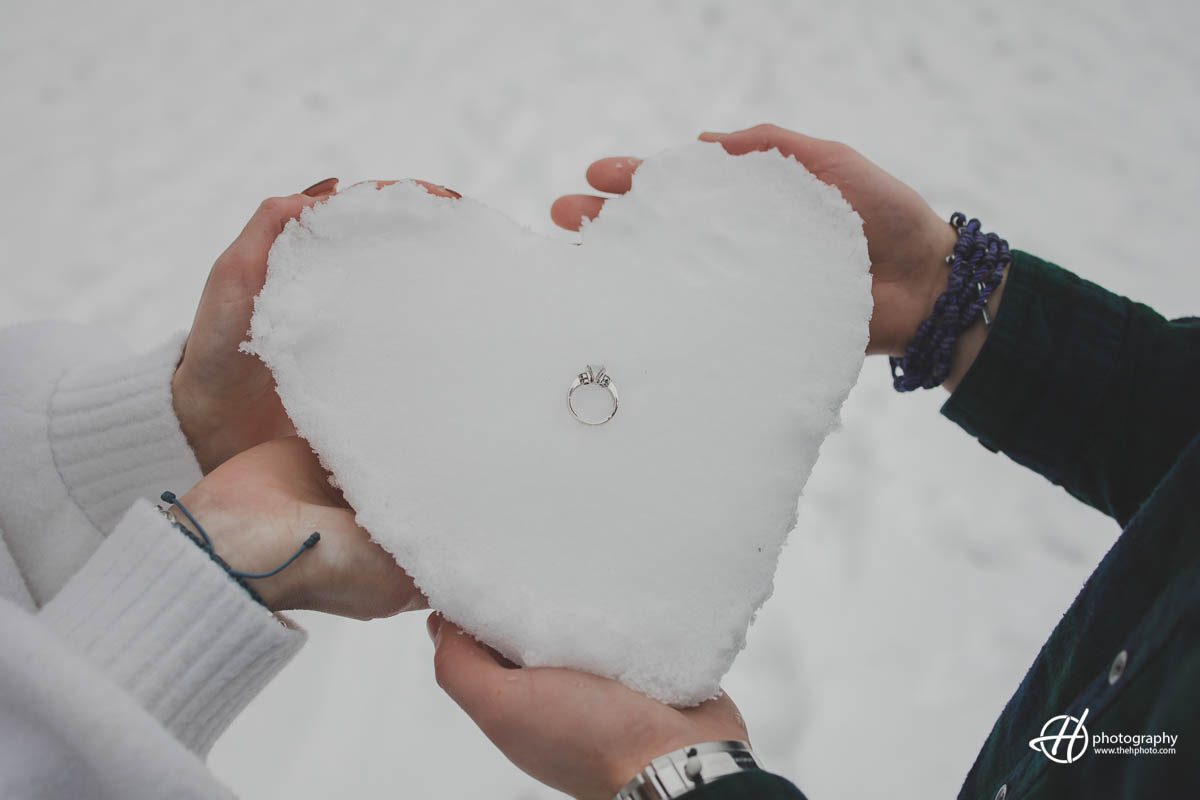 Image of the couple's creative winter-themed gesture of making a heart out of snow and placing the engagement ring in the middle, symbolizing their love and commitment to each other.